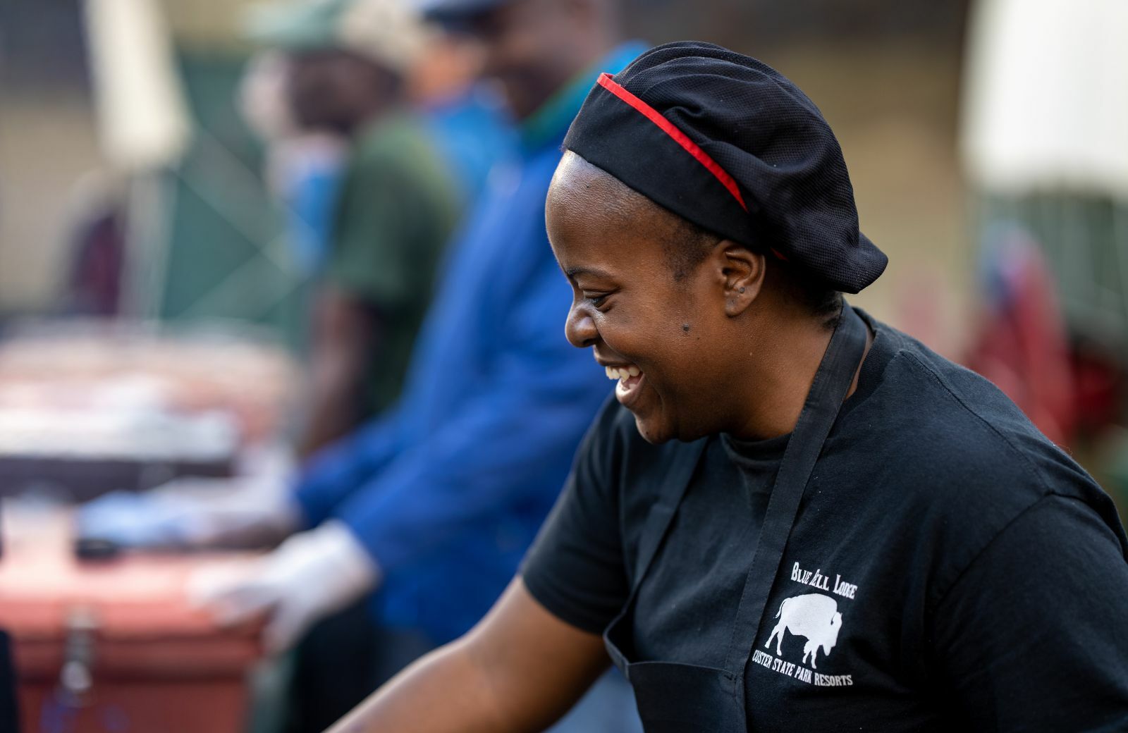An employee happily serves food at the cookout for bike week.