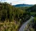 Aerial shot of a scenic road with hills and trees surrounding
