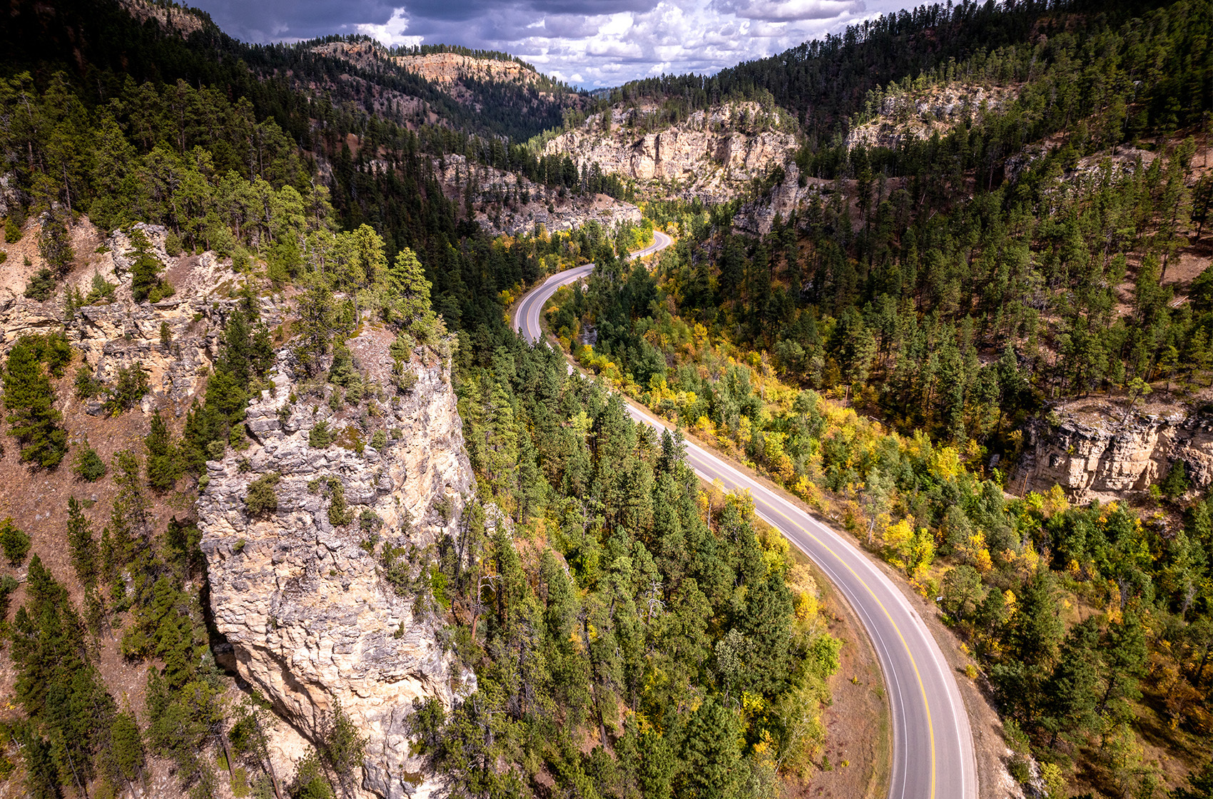 Aerial shot of a road with trees and hills surrounding