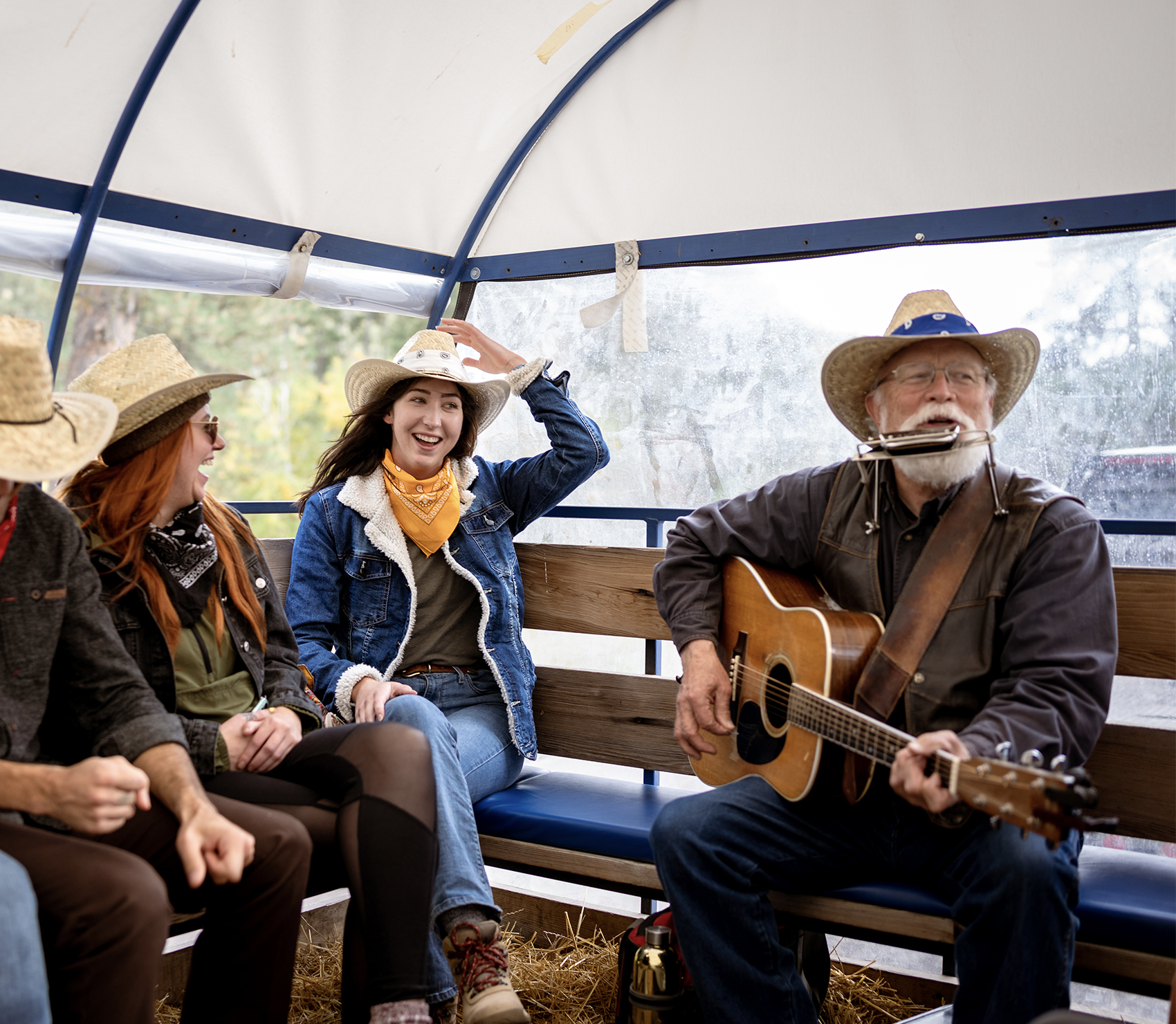 Man playing guitar and singing to a group in a wagon