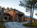 Exterior view of Sylvan Lake Lodge in Custer State Park, featuring rustic architecture with stone and wood siding. A curved driveway leads to the main entrance, surrounded by pine trees and well-kept grounds.