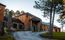 Exterior view of Sylvan Lake Lodge in Custer State Park, featuring rustic architecture with stone and wood siding. A curved driveway leads to the main entrance, surrounded by pine trees and well-kept grounds.