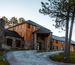 Exterior view of Sylvan Lake Lodge in Custer State Park, featuring rustic architecture with stone and wood siding. A curved driveway leads to the main entrance, surrounded by pine trees and well-kept grounds.