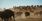 A herd of bison runs across a dusty plain beneath a clear sky, with riders on horseback in the distance.