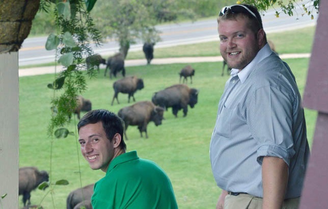 Two men looking back while watching the buffalo